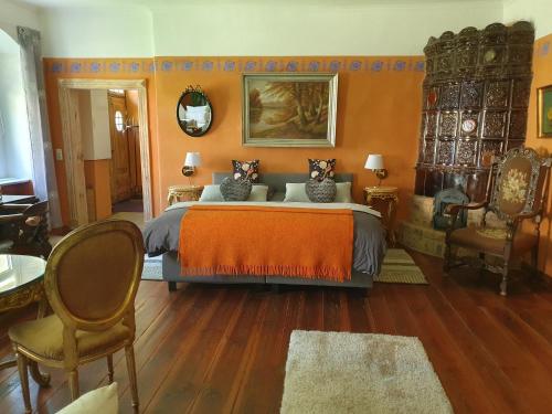 a bedroom with a large bed with orange walls and wooden floors at Gesindehaus am Schloss Kummerower See in Kummerow