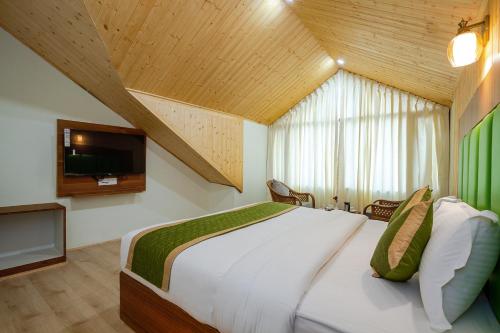 a bedroom with a large bed with a tv on the wall at Tripli Hotels Drilbu Manali in Manāli