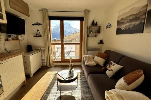 un salon avec un canapé et une grande fenêtre dans l'établissement Charmant Studio - Vue Montagne - Parking privé, à Les Deux Alpes