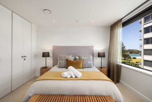 a bedroom with a large bed with two towels at Luxury Ocean & Harbour Views - Heated Pool, Main Beach & Gym in Mount Maunganui