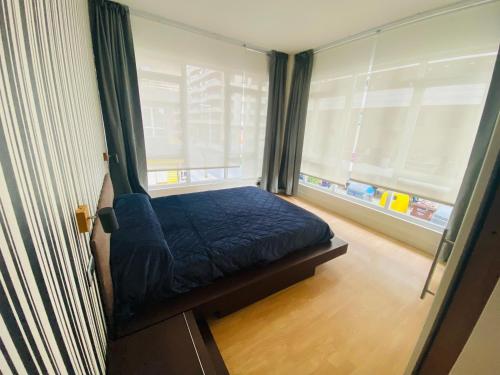 a small bedroom with a blue bed and a window at central apartment in Santurce