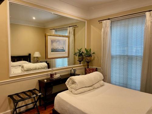 1 dormitorio con cama y espejo en Tintagel Guesthouse en Ciudad del Cabo