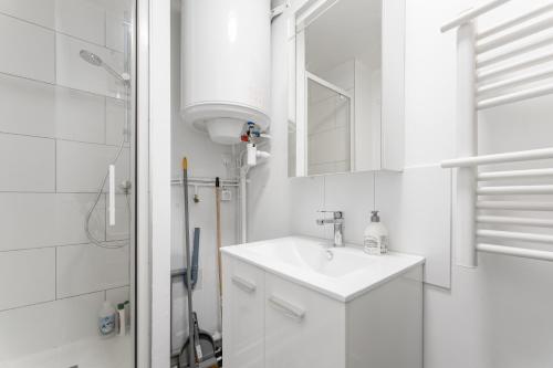 een witte badkamer met een wastafel en een douche bij Studio Confortable avec Parking gratuit dans la rue - Quelques pas de la gare, cuisine, WIFI in Arras