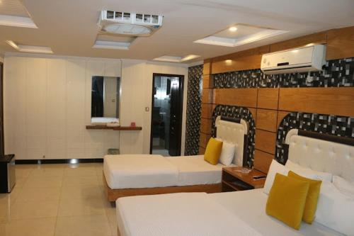 una habitación de hotel con 2 camas en una habitación en Beverly Inn Hotel, en Lahore