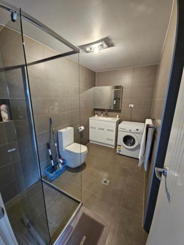 a bathroom with a shower and a toilet and a washing machine at New self-contained one bedroom within a house in Queanbeyan