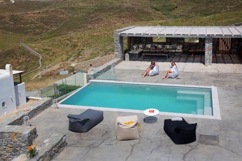 two women are sitting next to a swimming pool at Cabana Seaview Pool Villas w Night Security Guard, near Alemagou beach in Elia
