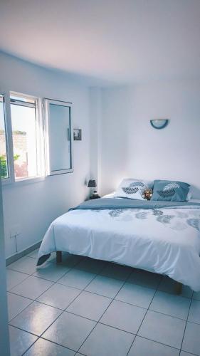 une chambre blanche avec un grand lit et une fenêtre dans l'établissement La Villa Marcel, au Barcarès