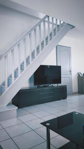 - un salon avec une télévision et un escalier dans l'établissement La Villa Marcel, au Barcarès