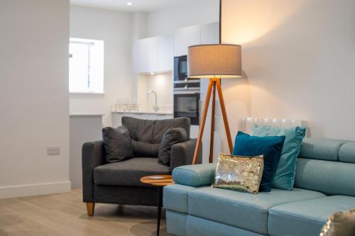 a living room with a blue couch and a chair at 15 Woolacombe East @Byron in Woolacombe
