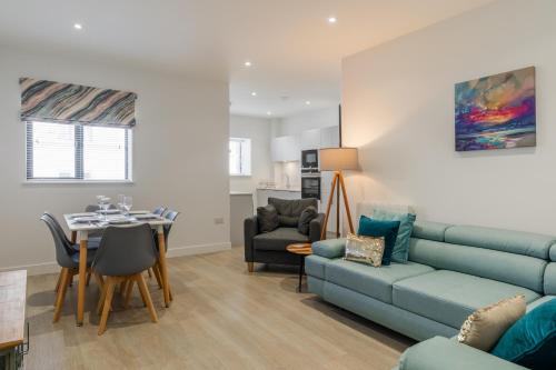 a living room with a blue couch and a table at 15 Woolacombe East @Byron in Woolacombe