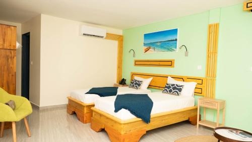 een slaapkamer met een bed en een gele stoel bij Jade hôtel and spa in Bandrélé