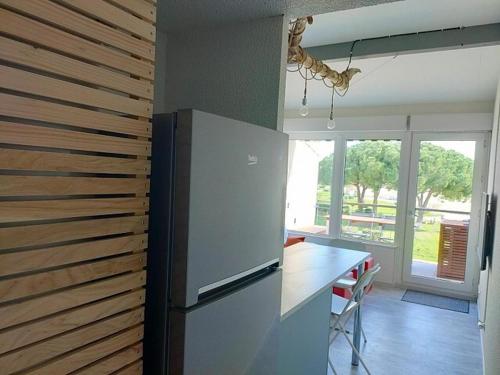 Il comprend une cuisine équipée d'un réfrigérateur et d'une table avec des chaises. dans l'établissement Appartement Vue d'Or les pieds dans l'eau, à La Londe-les-Maures
