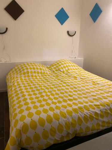 un lit jaune et blanc avec des carrés bleus sur le mur dans l'établissement Grand chalet tout équipé 6 personnes proche des plages du débarquement, à Sommervieu