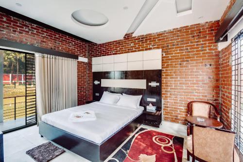 1 dormitorio con cama y pared de ladrillo en Kokomo Sunset Resort en Gazipur