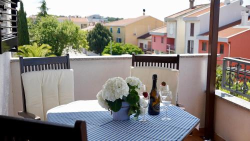 - une table avec une bouteille de vin et des fleurs sur le balcon dans l'établissement Apartments Ivo Rovinj Croatia, à Rovinj