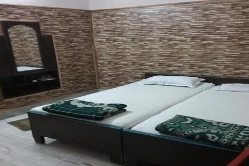 a bedroom with two beds and a mirror at Hotel Teerth Guest House Inn Varanasi in Varanasi