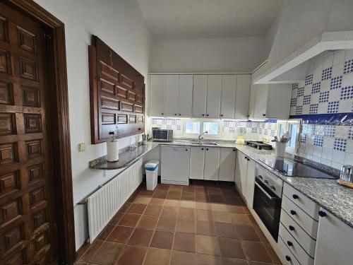 a large kitchen with white cabinets and a brown door at Finca Altair in Madrid
