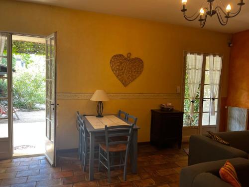 a living room with a table and a heart on the wall at Le Mas de Trévouse in Saint-Saturnin-lès-Avignon