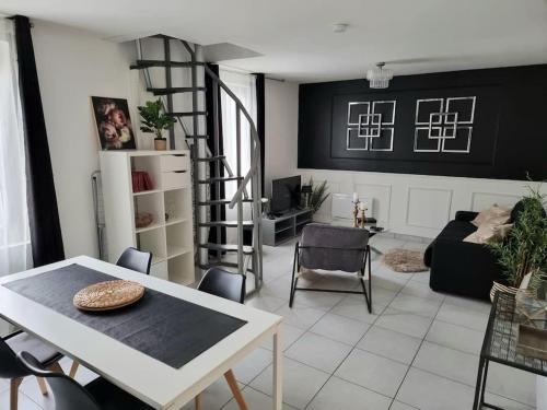 ein Wohnzimmer mit Tisch und Wendeltreppe in der Unterkunft Maison aux portes de Tours in Saint-Pierre-des-Corps