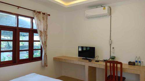 Pai Family Resort في باي: غرفة بها مكتب مع تلفزيون ونافذة