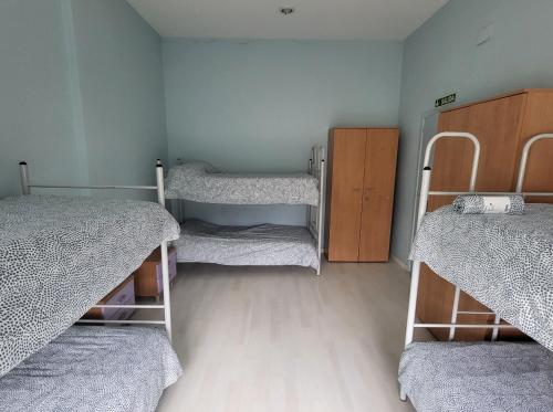 a room with three bunk beds and a wooden floor at Albergue de Guardo in Guardo