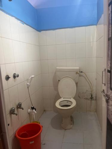 a bathroom with a toilet and a red bucket at Hotel Madhura in Belgaum
