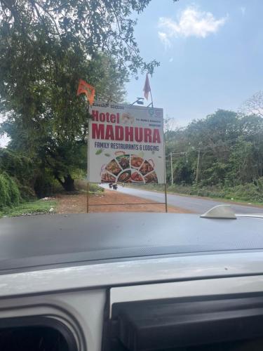 a sign on the side of a road at Hotel Madhura in Belgaum