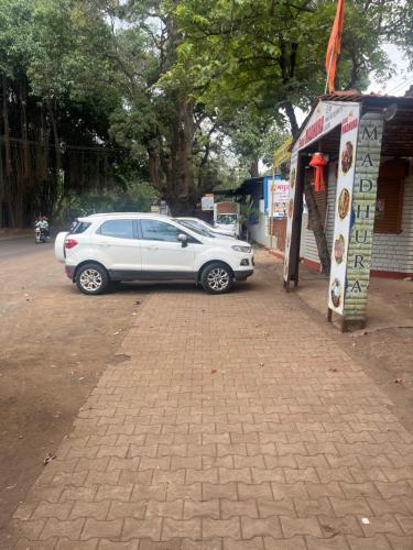 a white car parked in front of a building at Hotel Madhura in Belgaum