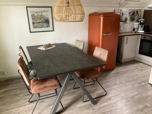 einen Esstisch mit Stühlen und einen Kühlschrank in der Unterkunft Schönes Ferienhaus in Oostmahorn (176) in Anjum