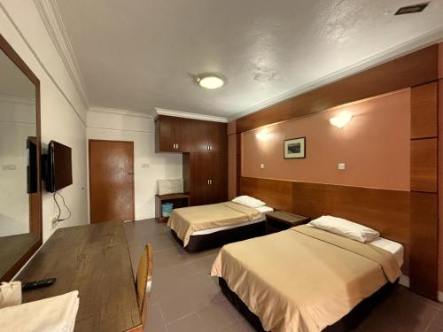 a hotel room with two beds and a tv at Cool Point Hotel in Tanah Rata