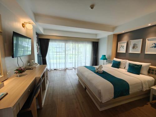 a hotel room with a large bed and a television at Phang Nga Shore Hotel in Khao Lak