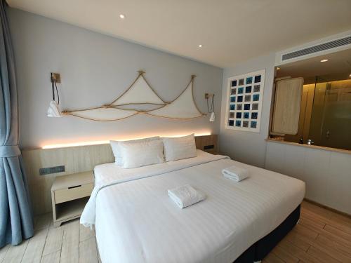 1 dormitorio con 1 cama blanca grande con almohadas blancas en Phang Nga Shore Hotel en Khao Lak