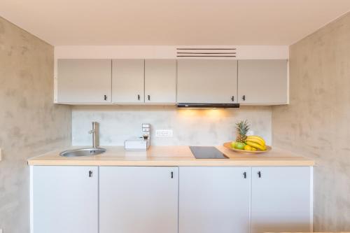 a kitchen with white cabinets and a bowl of fruit at Cabana Seaview Pool Villas w Night Security Guard, near Alemagou beach in Elia