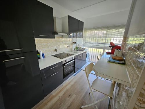 een keuken met zwarte kasten en een tafel met stoelen bij Antibes studio Vauban dernier étage vue mer in Antibes