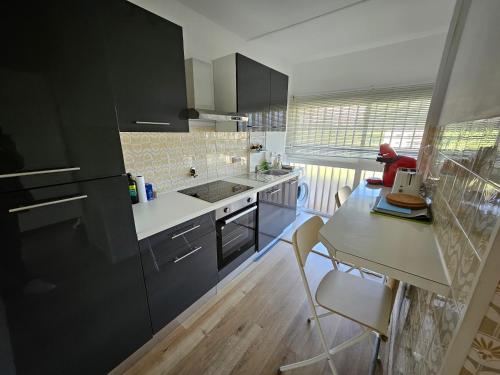 une cuisine avec des armoires noires et une table avec des chaises dans l'établissement Antibes studio Vauban dernier étage vue mer, à Antibes