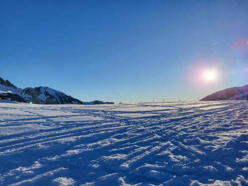 a snow covered field with the sun in the background at Le reposoir in Mont-Saxonnex