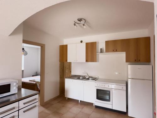 a small kitchen with white cabinets and a sink at Appartamenti LITEGOSA casa vacanza 2 in Panchia