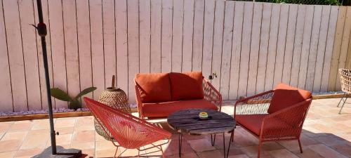 a patio with two chairs and a table and a chair and an umbrella at Chambres d'hôtes Un Eté Sans Fin à 50 m de la plage à Canet plage in Canet-en-Roussillon
