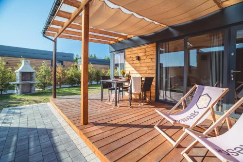 a wooden deck with a table and chairs on it at RResort Holiday Homes - HEATED Swimming Pool & Sauna in Rewal