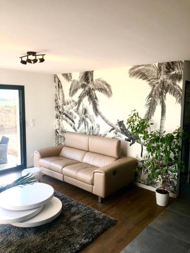 - un salon avec un canapé et une fresque murale de palmiers dans l'établissement House of SPA Courseulles Sur Mer, à Courseulles-sur-Mer