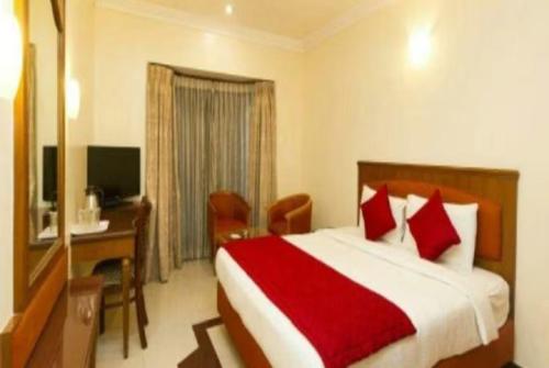 瓦拉納西的住宿－GRG Ashiyana Palace Parade Kothi Road Varanasi，酒店客房配有一张床、一张书桌和一台电视。