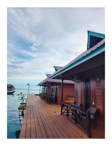 a wooden dock with a house on the water at Miranda Cottage in Derawan Islands