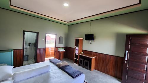a bedroom with a bed and a tv on the wall at Miranda Cottage in Derawan Islands