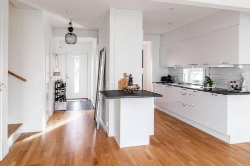 a white kitchen with white cabinets and a wooden floor at Strandnära uthyrning i Båstad in Båstad