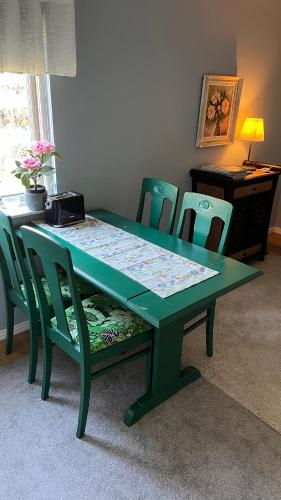 a green dining room table with chairs and a table with a bench at Fint boende i vackra Marielund in Uppsala