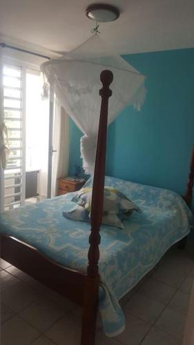 1 cama con dosel en un dormitorio azul en Résidence de la Baie : Superbe appartement en Le Marin