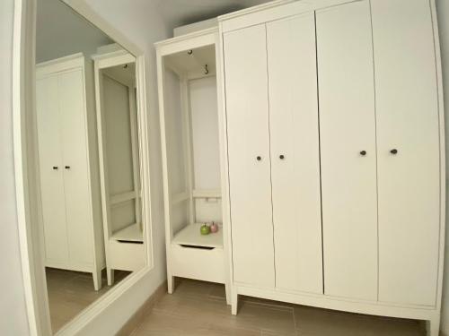 a white closet with white cabinets and a mirror at Villa Air - Relax, close to bossa beach, spacious rooms and private pool in Sant Jordi