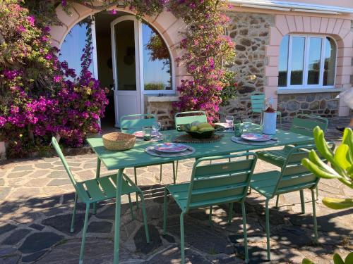a green table and chairs in a yard with flowers at Rayol vue mer jardin plage à pied - St-Tropez 25km in Rayol-Canadel-sur-Mer