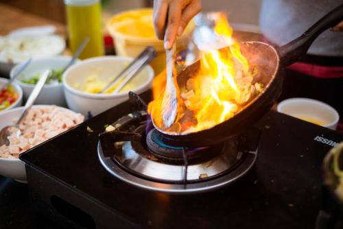 a person cooking food in a wok on a stove at Sand Sea Resort Railay Beach in Railay Beach