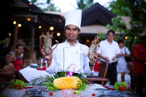 a man in a chef hat holding up two mason jars at Sand Sea Resort Railay Beach in Railay Beach